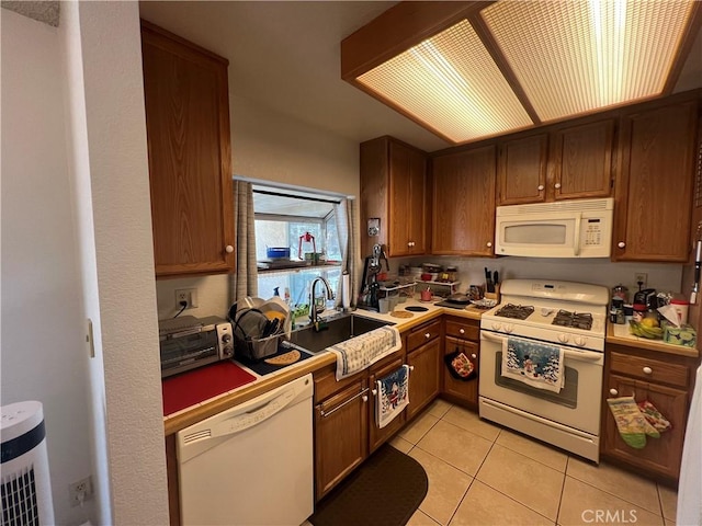 kitchen featuring white appliances, sink, and light tile patterned floors