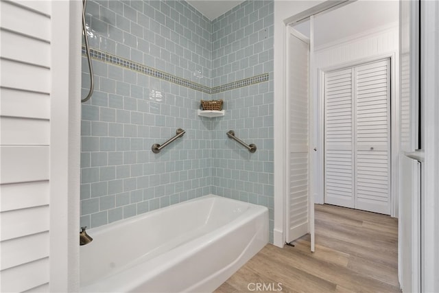 bathroom featuring wood-type flooring and tiled shower / bath