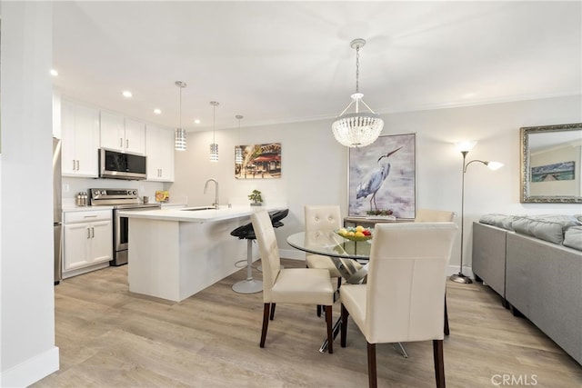 dining space with ornamental molding, sink, and light hardwood / wood-style floors