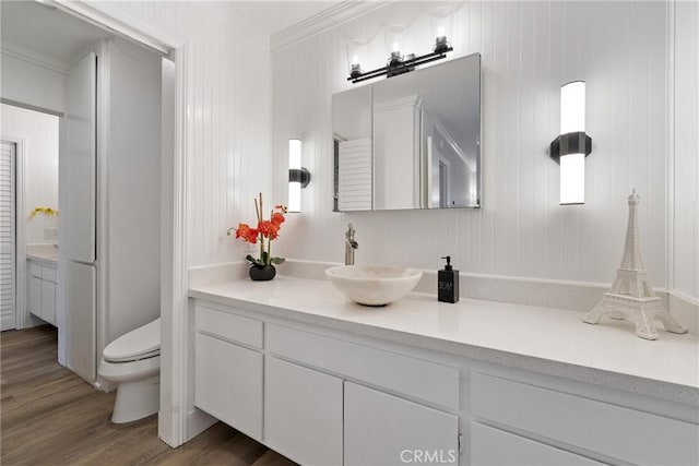 bathroom featuring hardwood / wood-style flooring, ornamental molding, toilet, and vanity