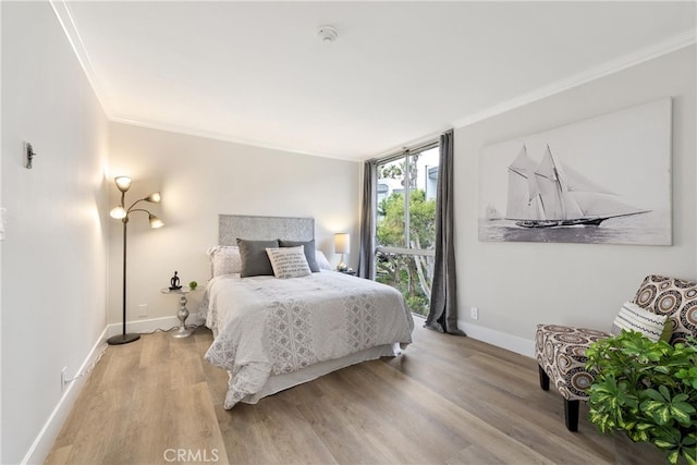 bedroom with hardwood / wood-style floors, crown molding, and expansive windows