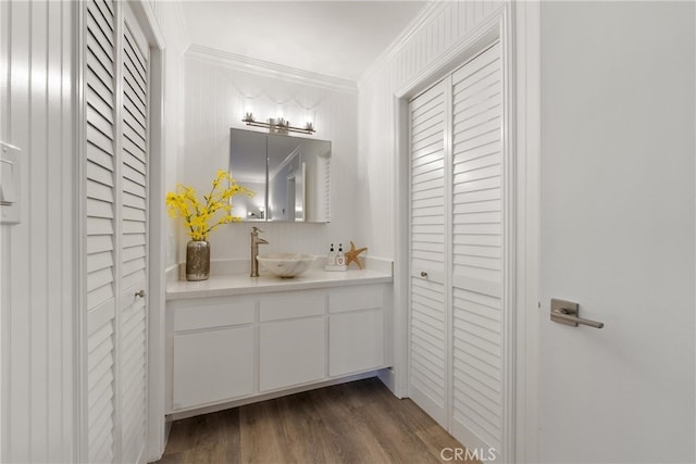 bathroom featuring crown molding, wood-type flooring, and vanity