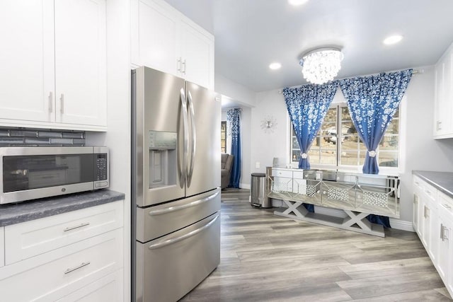 kitchen featuring white cabinetry, appliances with stainless steel finishes, a chandelier, and light wood-type flooring