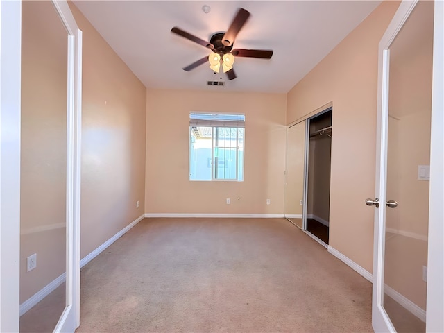 unfurnished bedroom with ceiling fan, light colored carpet, and a closet