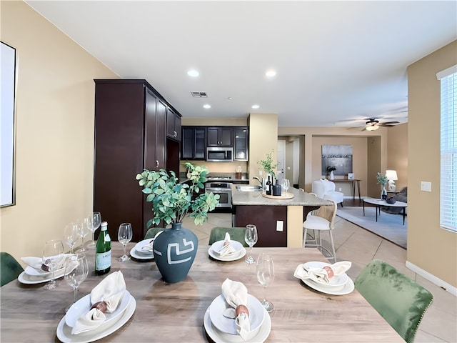 dining space featuring ceiling fan, sink, and light tile patterned floors