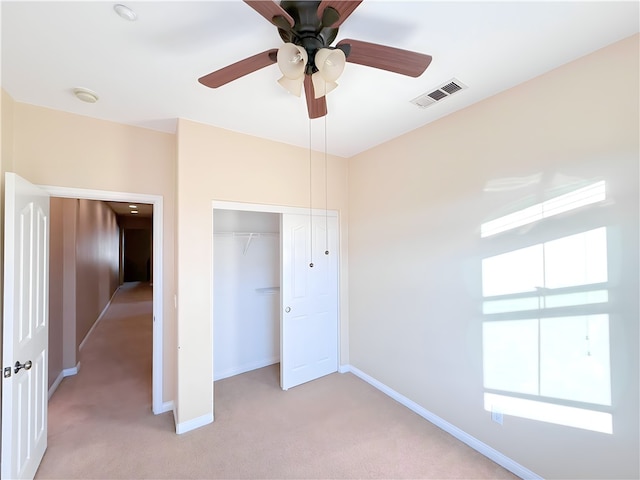 unfurnished bedroom with light colored carpet, a closet, and ceiling fan