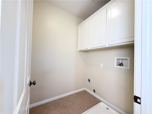 clothes washing area featuring light tile patterned flooring, cabinets, and washer hookup