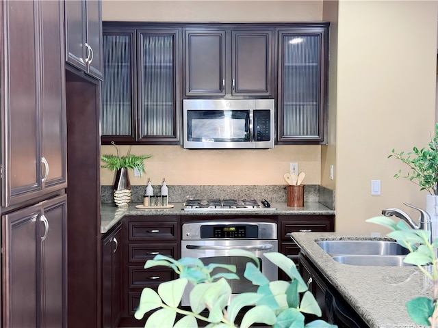 kitchen featuring light stone counters, appliances with stainless steel finishes, sink, and dark brown cabinets