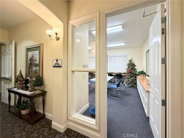 entryway featuring dark carpet and a chandelier