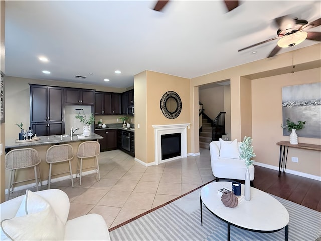 living room with ceiling fan, sink, and light tile patterned floors