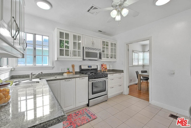 kitchen with light tile patterned flooring, ceiling fan, appliances with stainless steel finishes, and white cabinets