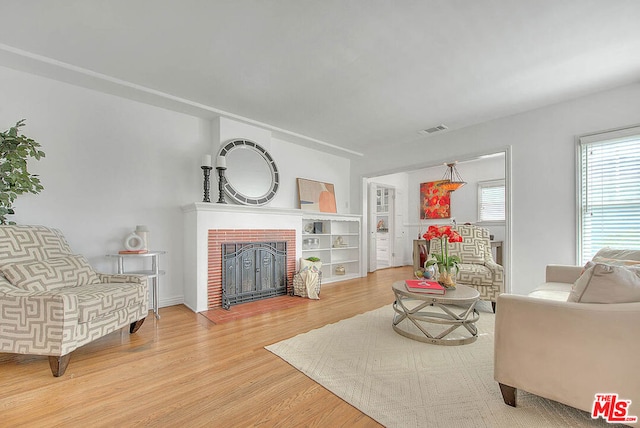 living room featuring a brick fireplace and hardwood / wood-style floors