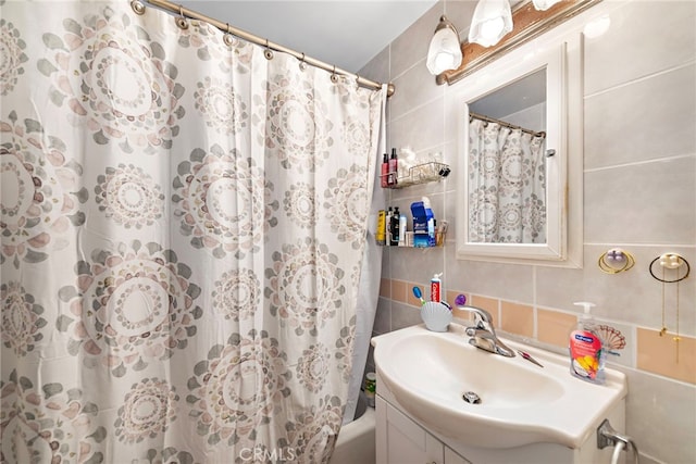 bathroom with tasteful backsplash, vanity, tile walls, and shower / tub combo with curtain