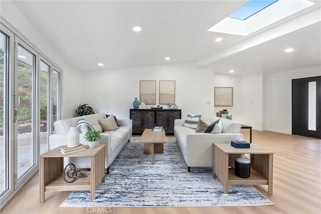 living room featuring beamed ceiling, light wood-type flooring, and a skylight