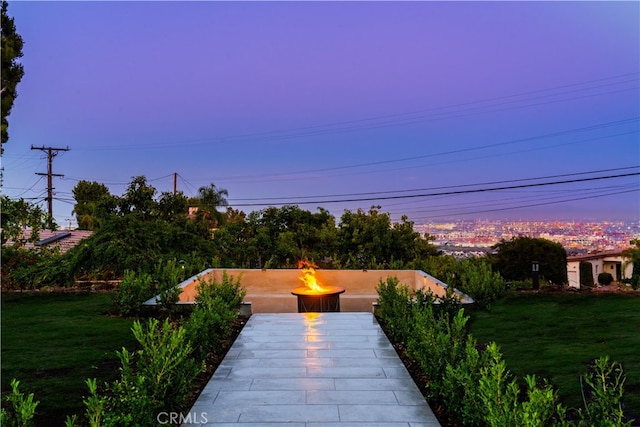 patio terrace at dusk featuring a lawn and an outdoor fire pit