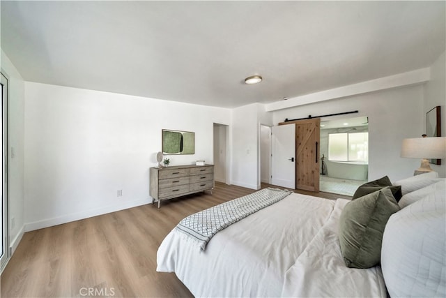 bedroom with a barn door and light hardwood / wood-style flooring