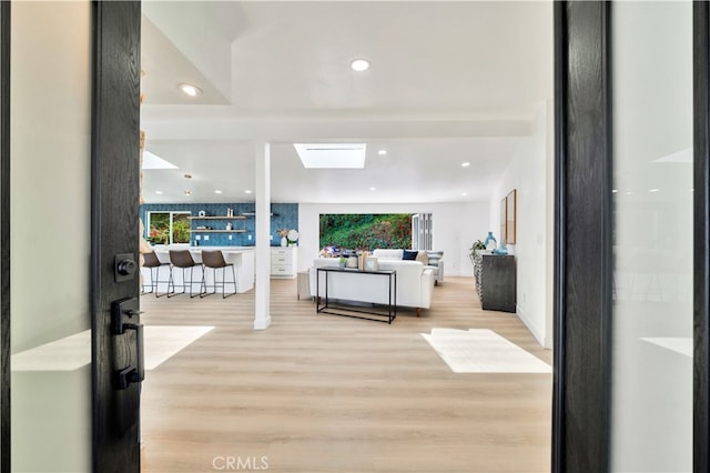 living room with a skylight and light hardwood / wood-style flooring