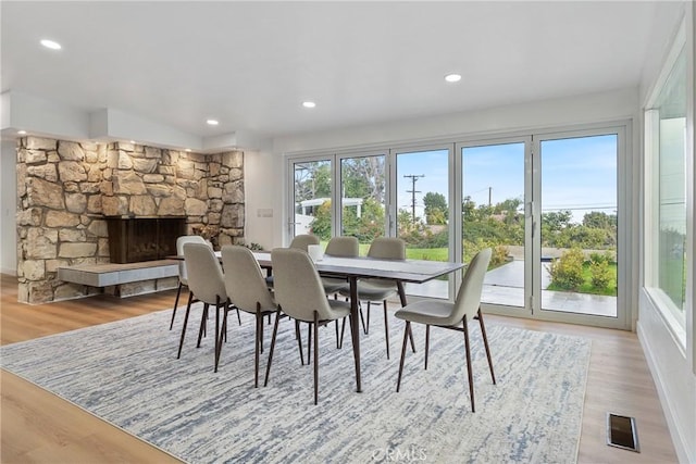 dining area with light wood-type flooring and a fireplace