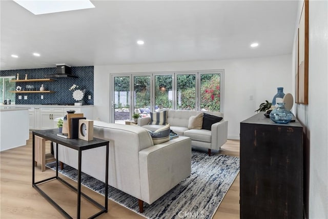 living room with light hardwood / wood-style floors and a skylight