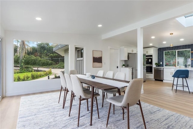 dining room with lofted ceiling with beams and light wood-type flooring