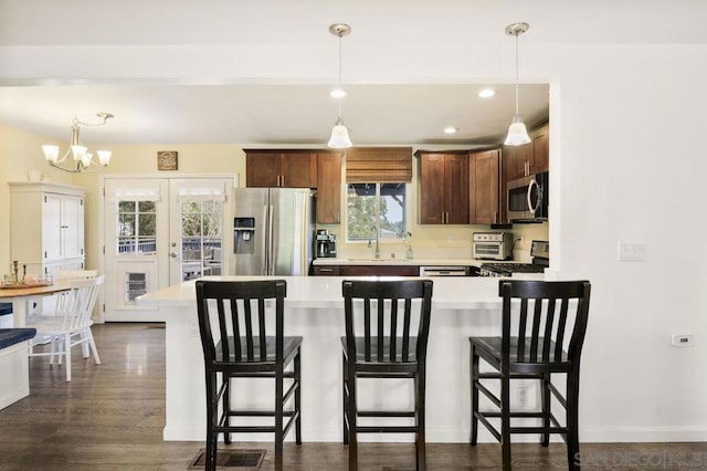 kitchen with stainless steel appliances, decorative light fixtures, a breakfast bar, and sink