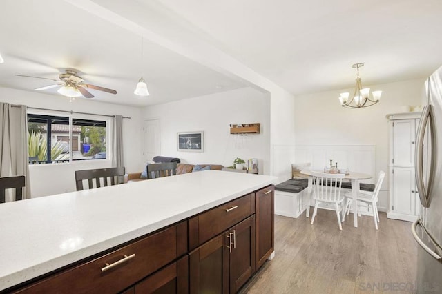 kitchen featuring hanging light fixtures, light wood-type flooring, stainless steel fridge, and dark brown cabinetry