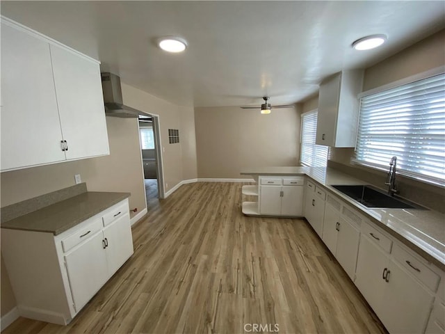 kitchen featuring sink, ceiling fan, white cabinetry, light hardwood / wood-style floors, and kitchen peninsula