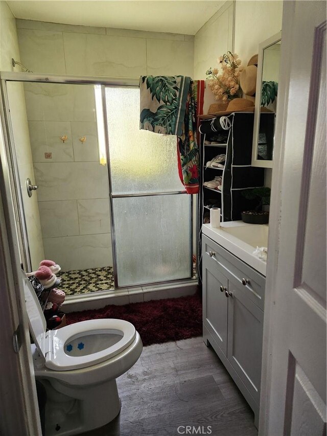 bathroom with an enclosed shower, vanity, hardwood / wood-style flooring, and toilet