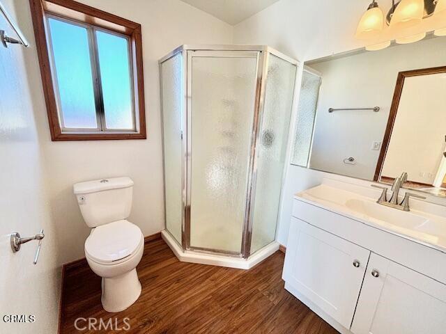 bathroom featuring wood-type flooring, toilet, an enclosed shower, and vanity