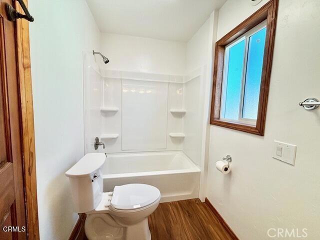 bathroom featuring wood-type flooring, toilet, and bathing tub / shower combination