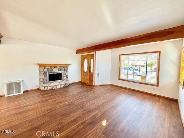 unfurnished living room featuring a stone fireplace, wood-type flooring, and beamed ceiling