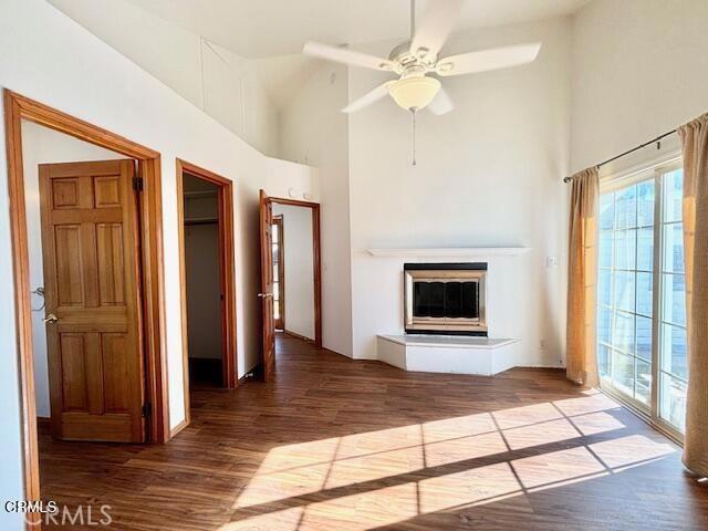 unfurnished living room featuring wood-type flooring, high vaulted ceiling, and ceiling fan