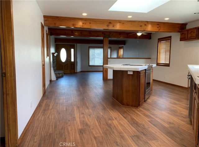 kitchen with beam ceiling, a skylight, a kitchen island, dark hardwood / wood-style flooring, and stainless steel electric stove