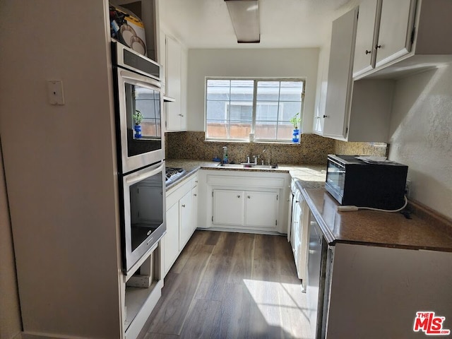 kitchen with sink, tasteful backsplash, appliances with stainless steel finishes, dark hardwood / wood-style flooring, and white cabinets