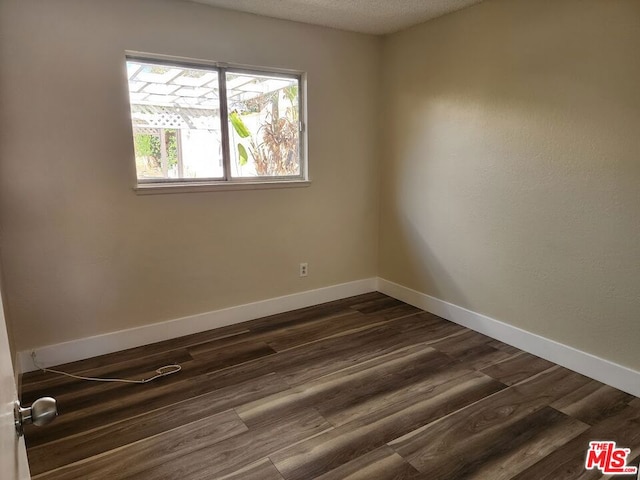 unfurnished room featuring a textured ceiling and dark hardwood / wood-style flooring