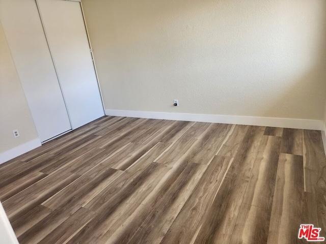 unfurnished bedroom with dark hardwood / wood-style flooring and a closet