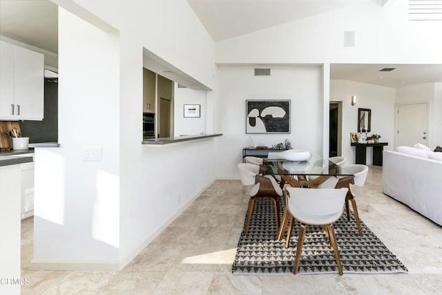 dining area featuring high vaulted ceiling