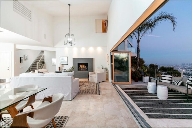 interior space featuring stairway, a lit fireplace, an inviting chandelier, and a towering ceiling