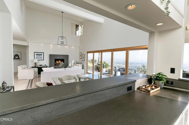 living area featuring a high ceiling and a warm lit fireplace