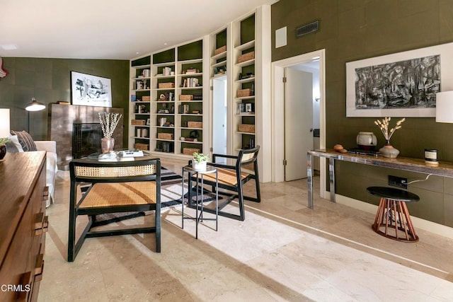 dining space with a glass covered fireplace, tile walls, built in features, and visible vents