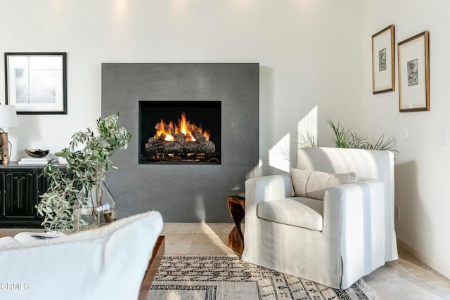 living area with baseboards and a lit fireplace