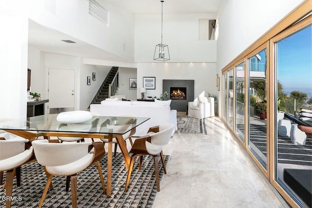 8326 Grand View Dr, Los Angeles, CA 90046 - dining area with stairs, a warm lit fireplace, a high ceiling, and light marble finish flooring