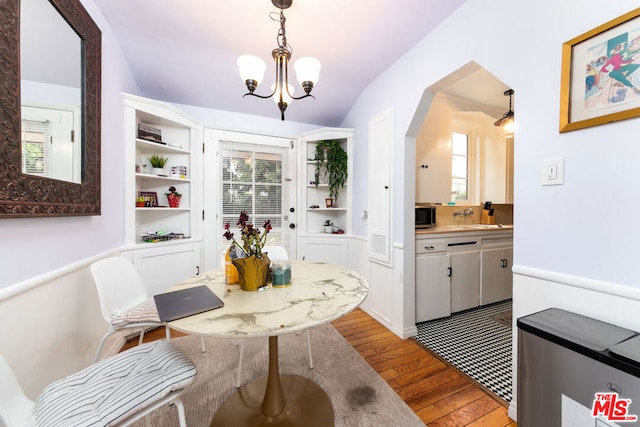 dining room featuring an inviting chandelier, lofted ceiling, sink, and light hardwood / wood-style flooring