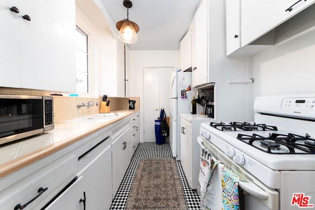 kitchen featuring white cabinetry, hanging light fixtures, white appliances, and tile counters