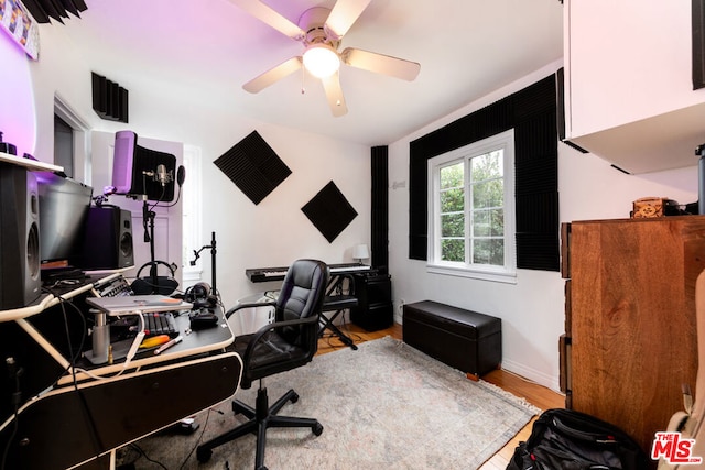 home office with light hardwood / wood-style floors and ceiling fan