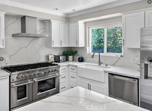 kitchen featuring sink, white cabinetry, stainless steel appliances, light stone countertops, and wall chimney range hood