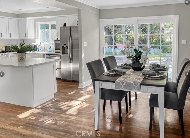 dining area with crown molding, sink, and hardwood / wood-style flooring