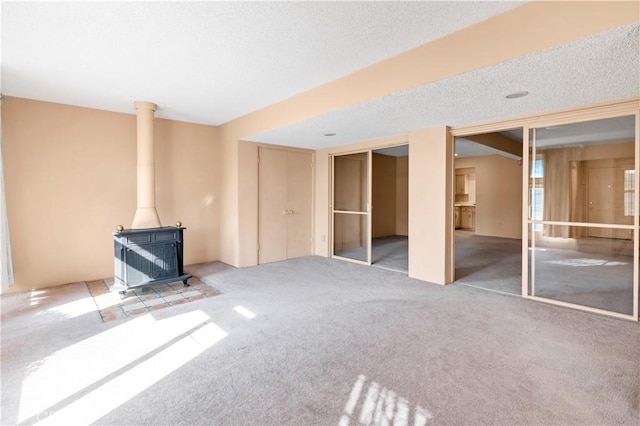 332 E 7th St, San Jacinto, CA 92583 - unfurnished living room featuring carpet flooring, a textured ceiling, and a wood stove