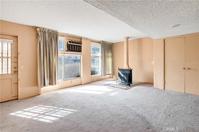 332 E 7th St, San Jacinto, CA 92583 - unfurnished living room with a wood stove, light colored carpet, and a textured ceiling