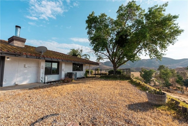 view of yard featuring fence, a mountain view, and cooling unit